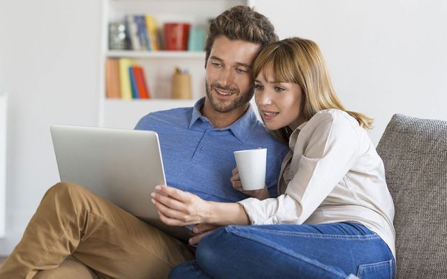 couple on couch looking at new homes on laptop
